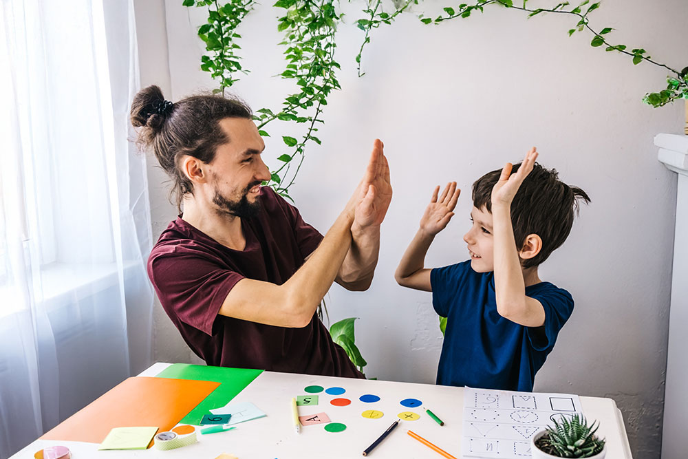 Happy autism boy during therapy with school tutor, learning and having fun together