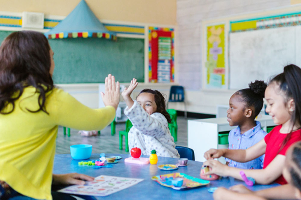 Kids sitting at a table across from their teacher at a nonpublic agency NPA