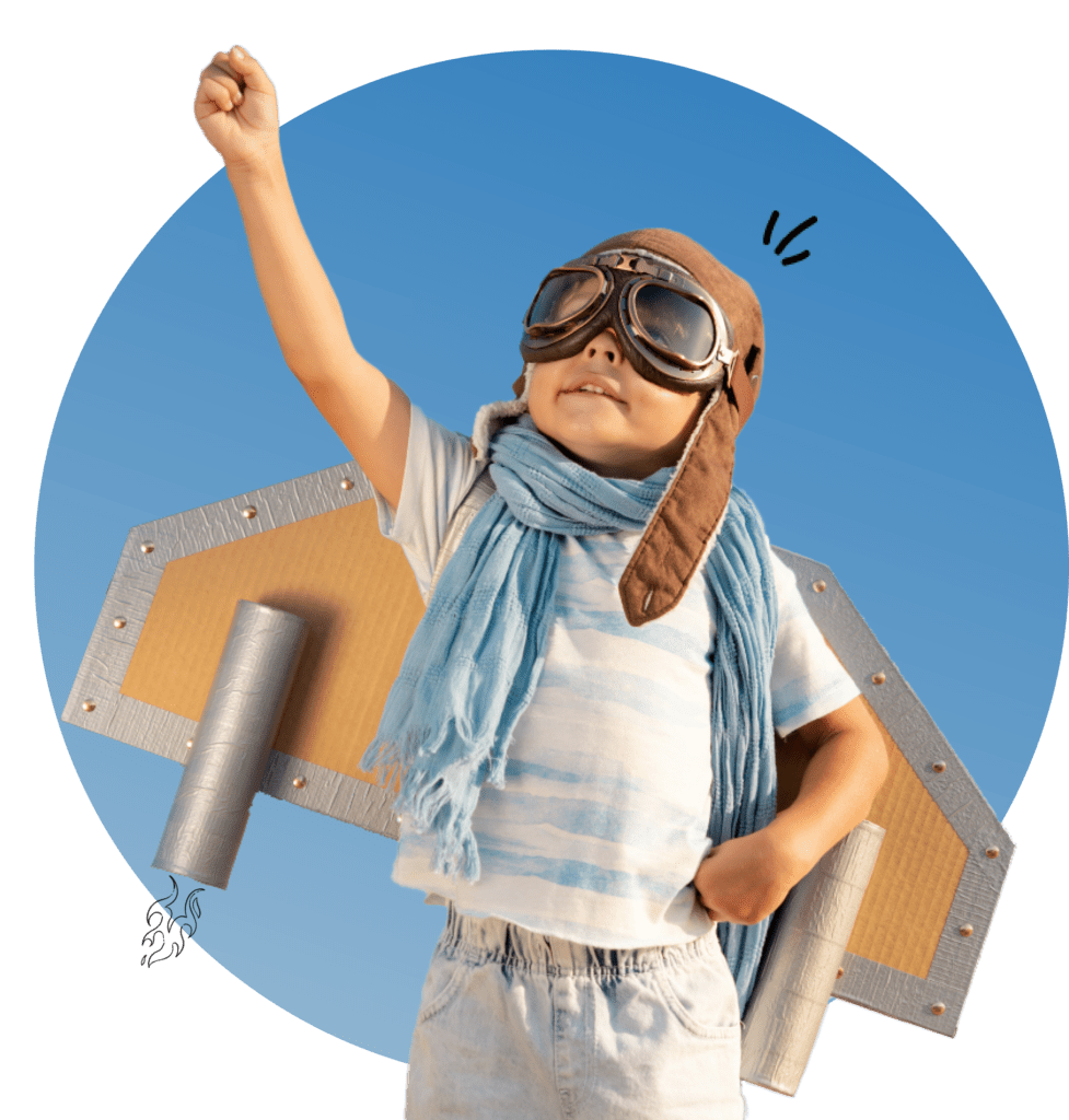 A young boy with cardboard wings on and a old fashion fighter hat and goggles with his fist in the air